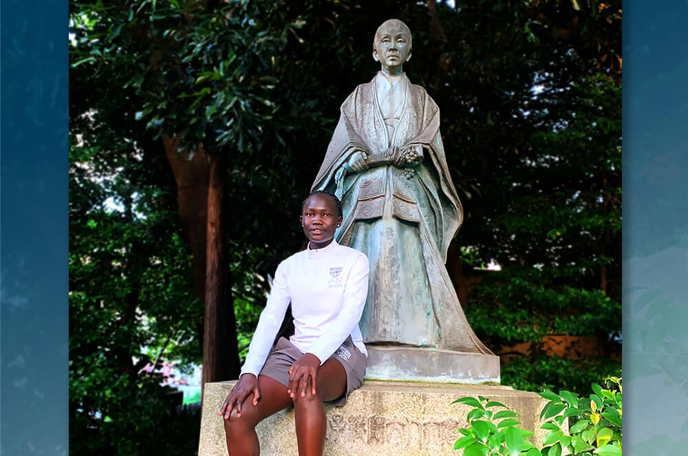 Woman in white long-sleeved shirt sitting in front of statue outside